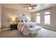 Comfortable primary bedroom with ceiling fan and windows, well-lit with a decorative bench at the foot of the bed at 15592 W Wesley Ave, Lakewood, CO 80228