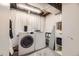 Functional laundry room with washer, dryer, storage shelves and cabinets with ironing board for a streamlined laundry process at 6267 S Albion Ct, Centennial, CO 80121