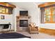 Comfortable bedroom with a stone fireplace, plush seating, and large windows offering natural light at 32217 Buffalo Park Rd, Evergreen, CO 80439
