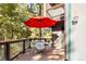 Outdoor dining area on the deck with a round table, four chairs, bright red umbrella, and lush, surrounding nature at 32217 Buffalo Park Rd, Evergreen, CO 80439