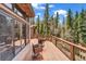 Expansive deck with wood railing features seating area, views of the surrounding pine forest, and glass door access to the home at 32217 Buffalo Park Rd, Evergreen, CO 80439