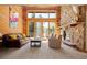 Bright living room featuring a stone fireplace, wood paneled walls, and a large sliding glass door at 32217 Buffalo Park Rd, Evergreen, CO 80439