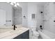 Well-lit bathroom featuring a blue vanity, marble tile backsplash, and a shower-tub combo at 5773 S Benton Way, Littleton, CO 80123