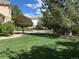 Beautifully landscaped front yard featuring a lush lawn, mature trees, and decorative fence, enhancing curb appeal at 5773 S Benton Way, Littleton, CO 80123