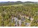 Expansive aerial view of a property with multiple buildings, a firepit area, nestled among lush trees and a winding road at 10887 Goodheart Ave, Conifer, CO 80433