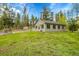 Well-maintained home featuring a lush green lawn, complemented by a charming exterior and surrounding tall trees at 10887 Goodheart Ave, Conifer, CO 80433