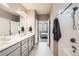 Bright bathroom featuring a dual sink vanity and access to a well-lit bedroom and shower at 8953 Falcon St, Firestone, CO 80504