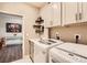 The laundry room features modern washer and dryer with upper cabinets and a sink at 8953 Falcon St, Firestone, CO 80504