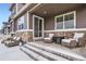 This charming patio offers two cushioned chairs, a table, and steps leading to the grassy yard at 8953 Falcon St, Firestone, CO 80504