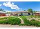 Inviting single-story home with a charming porch, set against a clear blue sky and lush green landscape at 1151 Revere St, Aurora, CO 80011