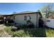 Exterior view of a single-story home with a covered front porch and side yard with overgrown grass at 1151 Revere St, Aurora, CO 80011