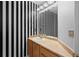 Charming half bathroom with wood vanity and black and white striped accent wall at 1160 S Fultondale Ct, Aurora, CO 80018