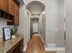Hallway featuring arched doorways, hardwood floors, and a built-in desk area with granite countertops at 6995 S Ensenada St, Aurora, CO 80016