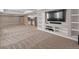 Open concept living room featuring built-in shelving, large screen TV, and adjacent kitchen area at 6995 S Ensenada St, Aurora, CO 80016