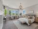 Spacious main bedroom featuring a seating area, large windows, carpeted floors, and elegant chandelier at 6995 S Ensenada St, Aurora, CO 80016