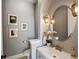 Stylish powder room with elegant lighting, framed artwork, modern vanity and round mirror at 6995 S Ensenada St, Aurora, CO 80016