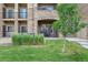 Building exterior with a green lawn, small tree, and units with balconies and a covered patio at 17442 Nature Walk Trl # 105, Parker, CO 80134