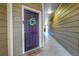 Condo front door with a wreath and welcome mat, leading to the unit's entrance and the hallway at 17442 Nature Walk Trl # 105, Parker, CO 80134