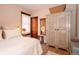 Bright bedroom with white walls, hardwood floors, a plush bed, an antique armoire, and a window at 669 S Washington St, Denver, CO 80209