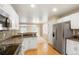 Well-lit kitchen with white cabinets, stainless steel appliances, and view into living room, creating open space at 19029 E 58Th Ave, Denver, CO 80249