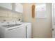 Well-equipped laundry room featuring a modern washer and dryer, storage shelves, and natural light from a window at 19029 E 58Th Ave, Denver, CO 80249