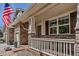 Inviting front porch with white railing, stone accents, and an American flag at 6345 S Ider Way, Aurora, CO 80016
