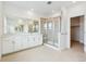 Bright bathroom featuring a double vanity, glass shower, and neutral tile flooring at 9322 Quaker St, Arvada, CO 80007