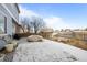 A snowy backyard features a patio, a covered item, and a wooden fence providing privacy at 12366 Nate Cir, Parker, CO 80134