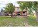 A well-kept backyard features a covered patio, green lawn, mature trees, and privacy fencing at 7552 Garland St, Arvada, CO 80005