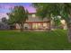 View of the backyard patio with seating, string lights, green lawn and mature trees at 7552 Garland St, Arvada, CO 80005