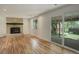 Open-plan living room with brick fireplace, hardwood floors, and sliding glass door to the backyard patio at 7552 Garland St, Arvada, CO 80005