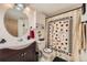 View of bathroom with updated vanity, toilet, white cabinets and playful card-themed shower curtain at 11746 Elizabeth Cir, Thornton, CO 80233