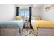 Bright bedroom featuring two twin beds with decorative pillows and a bright sunny window at 5735 N Genoa Way # 11-205, Aurora, CO 80019