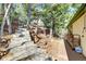 Exterior side view of the home showing a wooden deck, a staircase going uphill and natural surroundings at 33090 Janelle Cir, Golden, CO 80403