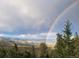 Wide landscape view featuring a double rainbow arching over a lush, green valley and mountains at 33090 Janelle Cir, Golden, CO 80403