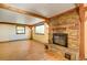 Open living room featuring a brick fireplace, wood floors, exposed beams, and a large window at 33090 Janelle Cir, Golden, CO 80403