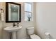 Powder room featuring pedestal sink, dark framed mirror, modern fixtures, and neutral paint at 8733 Arriba Dr, Littleton, CO 80125