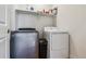 Practical laundry room featuring a front-load washer, a dryer and convenient shelving at 8733 Arriba Dr, Littleton, CO 80125