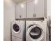 Laundry area with stacked washer and dryer and gray cabinets at 15376 Ivanhoe Ct, Thornton, CO 80602