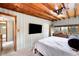 A well-lit bedroom features wood ceiling, ceiling fan, and large flat screen television at 4986 White House Trl, Evergreen, CO 80439