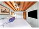 Comfortable bedroom featuring rustic wood ceiling, ceiling fan, and large flat screen television at 4986 White House Trl, Evergreen, CO 80439