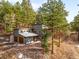 Modern home featuring gray siding, a two-car garage, and surrounded by a dense forest at 4986 White House Trl, Evergreen, CO 80439