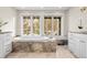 Soaking tub with marble surround and bench seat sits in front of two large windows at 50 Meade Ln, Cherry Hills Village, CO 80113
