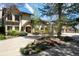 Elegant home with an arched entry, well-manicured landscaping, mature trees, and circular driveway offering curb appeal at 50 Meade Ln, Cherry Hills Village, CO 80113