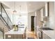 Open kitchen with light wood cabinets, quartz countertop island, stainless steel appliances, and modern light fixtures at 1822 Grove St # 110, Denver, CO 80204