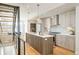Modern kitchen with gray wood cabinets, stainless steel appliances, island, and open staircase at 1822 Grove St # 110, Denver, CO 80204