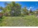 Large backyard featuring mature trees, grassy lawn, and garden area at 305 Cottonwood Ct, Longmont, CO 80501