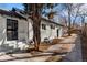 Exterior side view of white painted brick home with trees shading a long walkway on the right at 1858 S Lincoln St, Denver, CO 80210