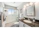 Bathroom boasts shower-tub combination with glass doors, granite countertops, and modern fixtures at 3582 Wright St, Wheat Ridge, CO 80033