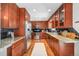 Galley kitchen features cherry cabinets, granite countertops, stainless steel appliances, and black tile backsplash at 3582 Wright St, Wheat Ridge, CO 80033